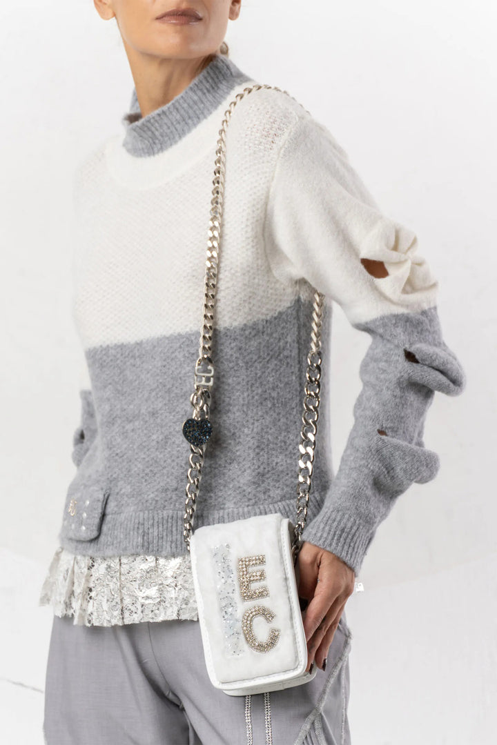 Person wearing a gray and white sweater with a white handbag featuring 'EC' initials.