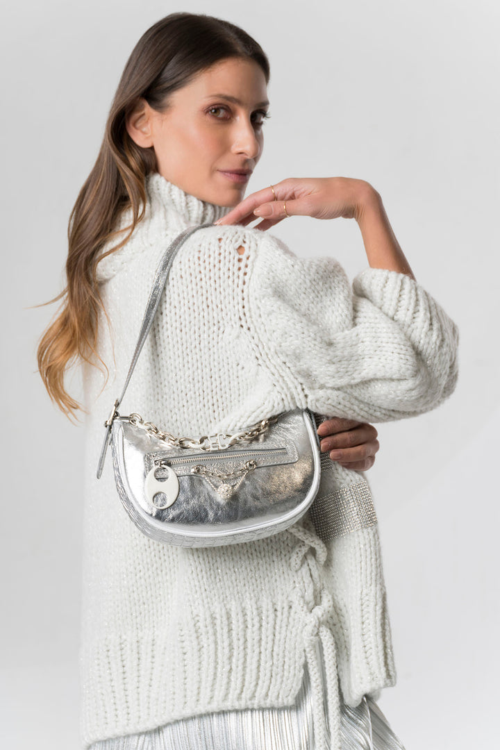 Woman holding a silver handbag against a plain background
