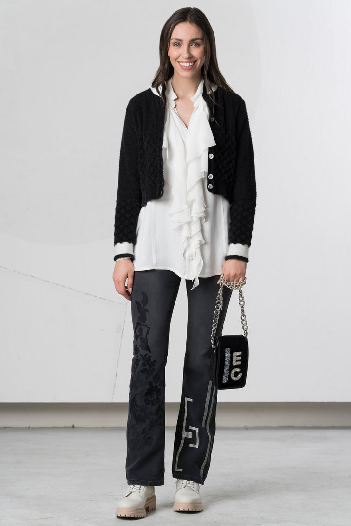 Woman wearing a black blazer, white shirt, and black pants with a white background