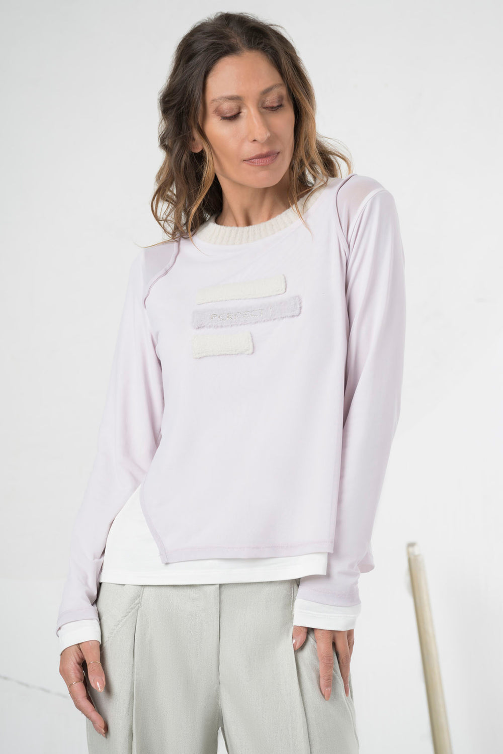Woman wearing a light purple long-sleeve top with a white pocket on a white background