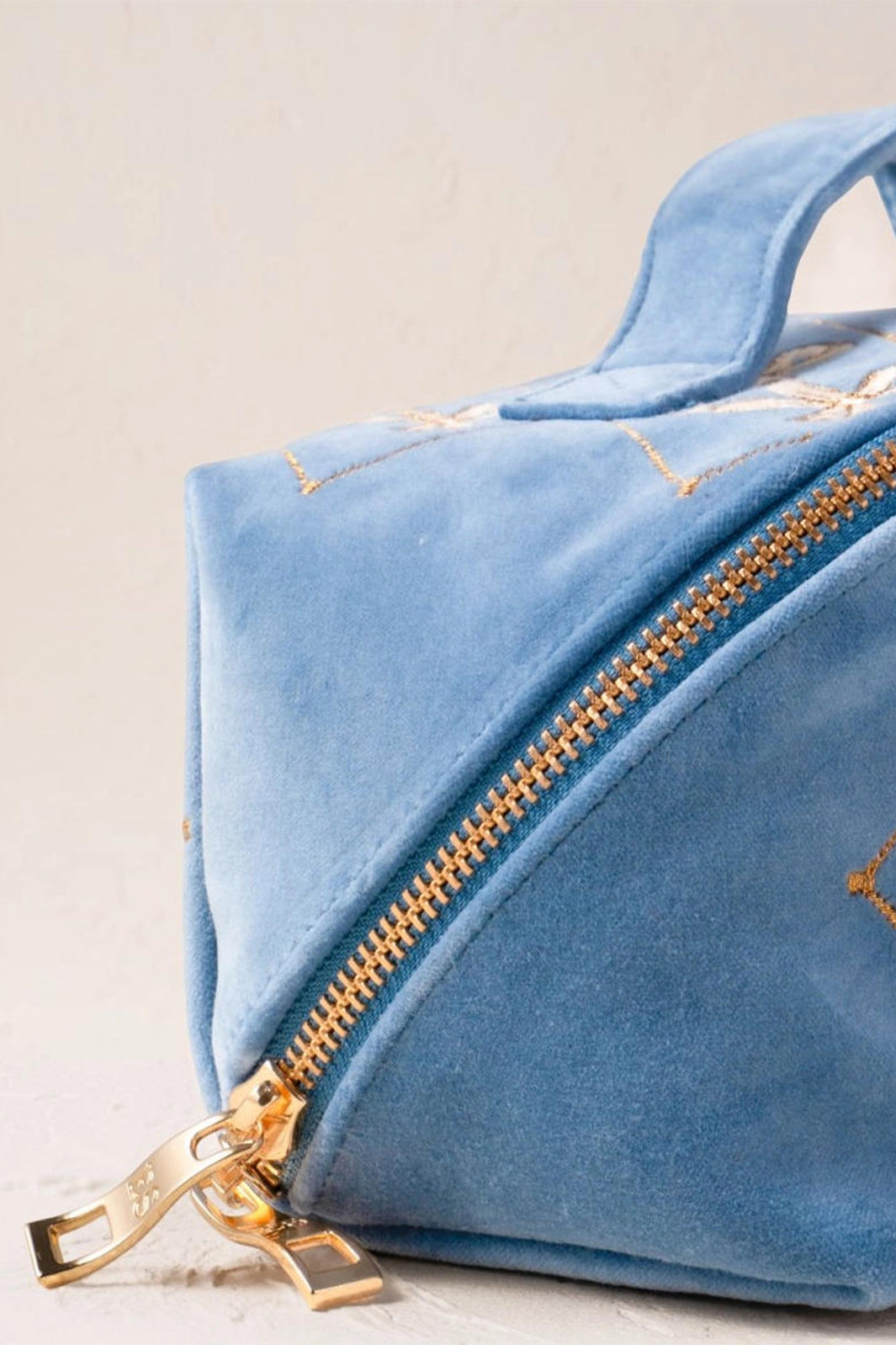Blue geometric bag with gold zipper on a light background