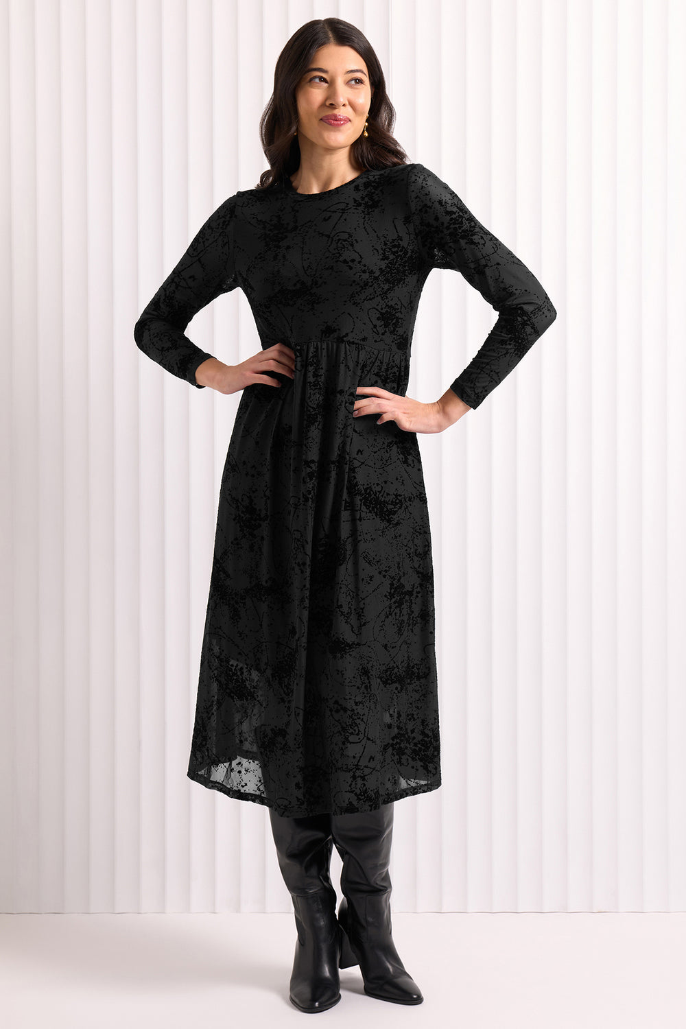Woman wearing a black dress with long sleeves against a white background