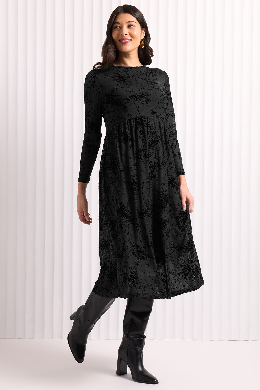 Woman wearing a black dress with a subtle pattern against a white background