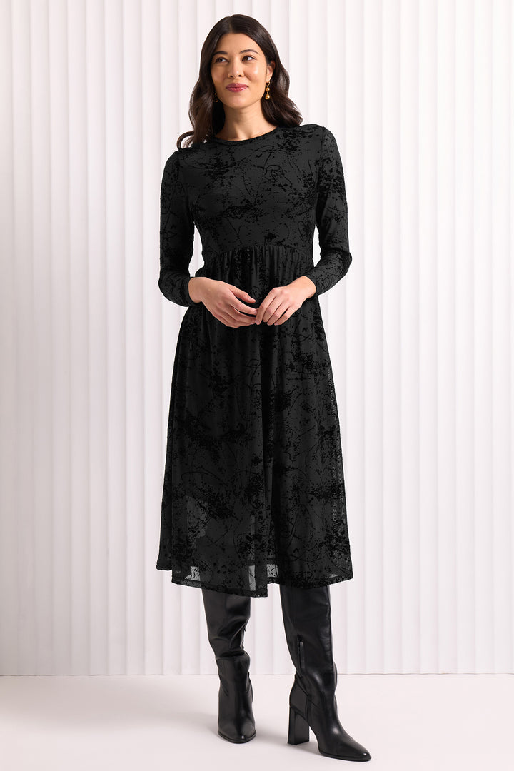 Woman wearing a black lace dress with long sleeves against a white background