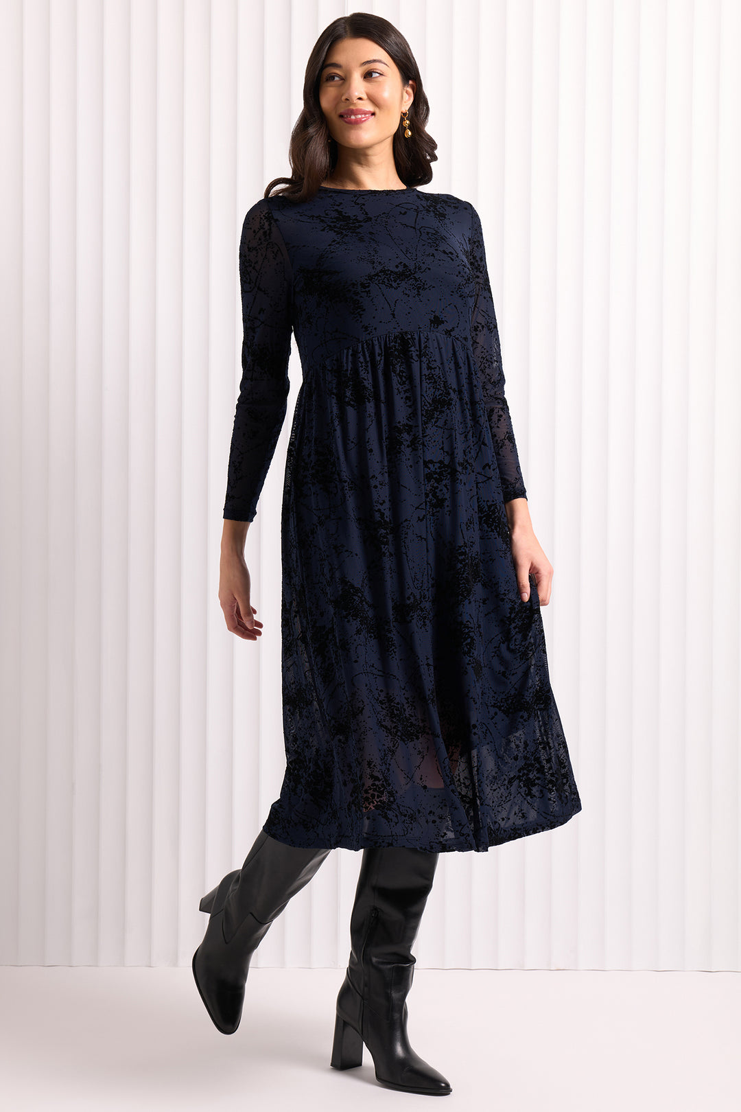 Woman wearing a dark blue dress with long sleeves against a white background