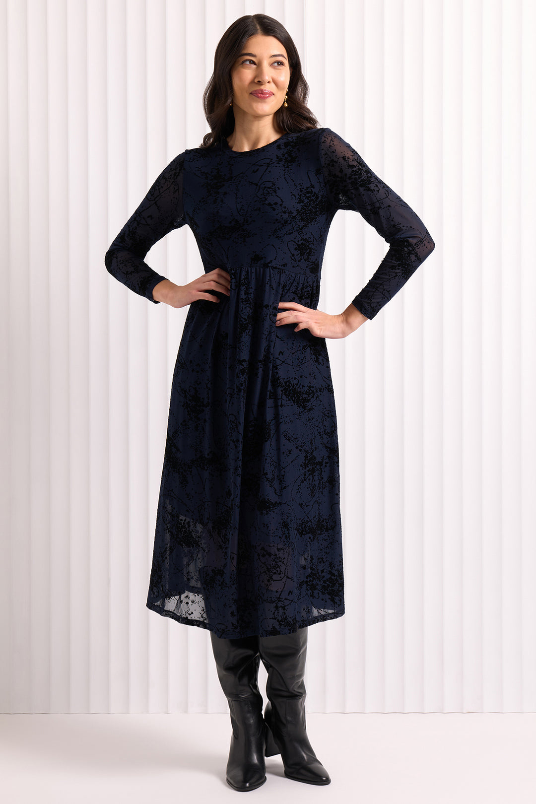Woman wearing a navy blue dress with long sleeves against a white background