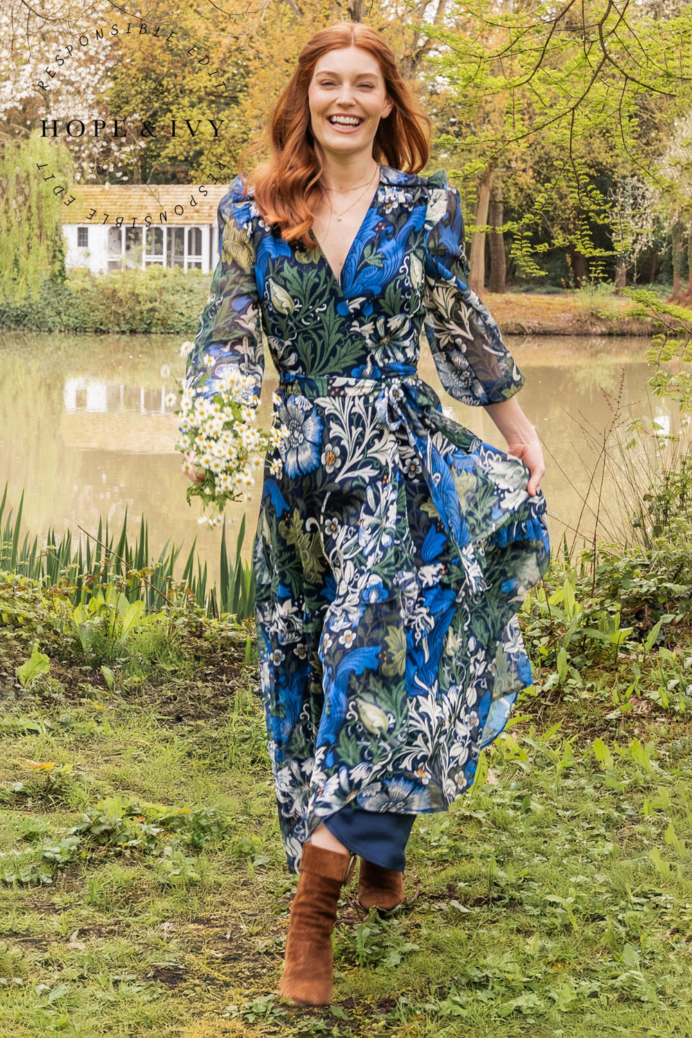 Woman in a floral dress standing by a pond with 'Hope & Ivy' branding.