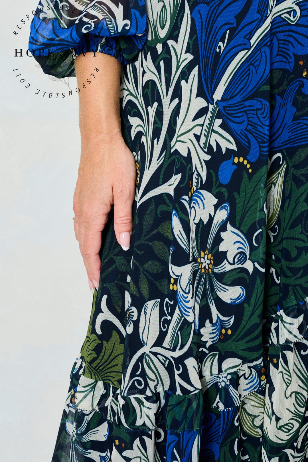 Close-up of a person wearing a floral patterned dress with blue, green, and white colors.