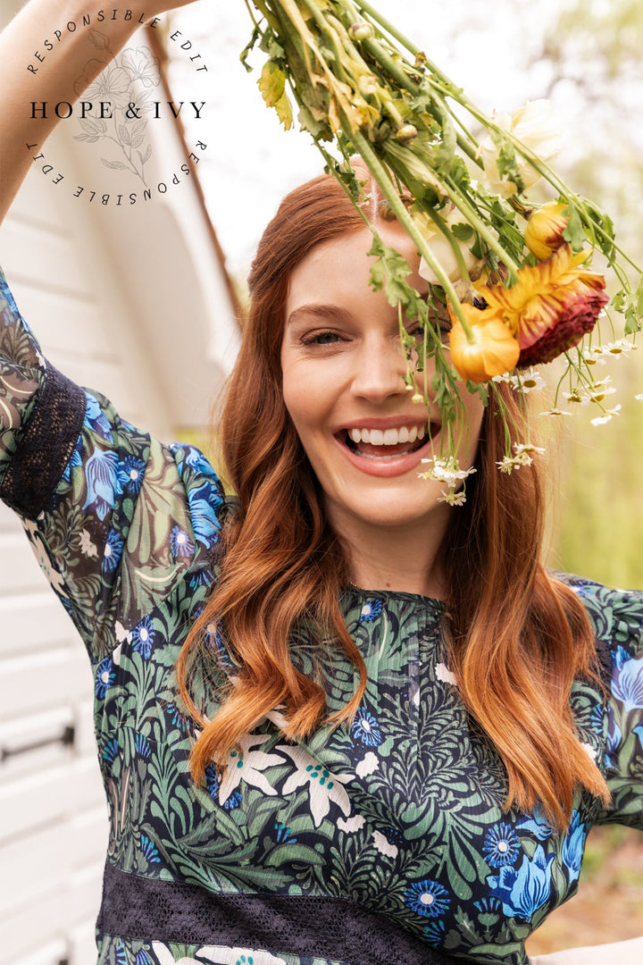 Woman holding a bouquet of flowers with 'Hope & Ivy' branding in the background.