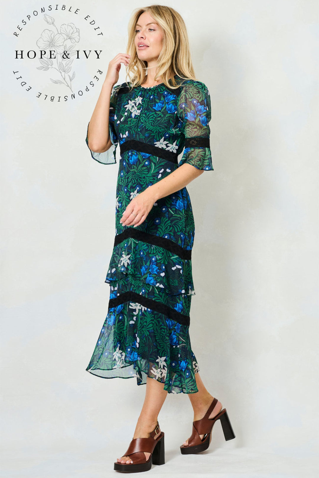 Woman wearing a floral dress with 'Hope & Ivy' branding on a white background