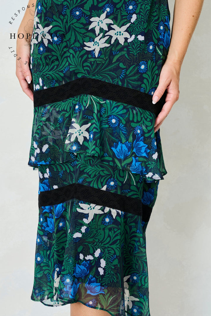 Green floral dress with black waistband on a plain background