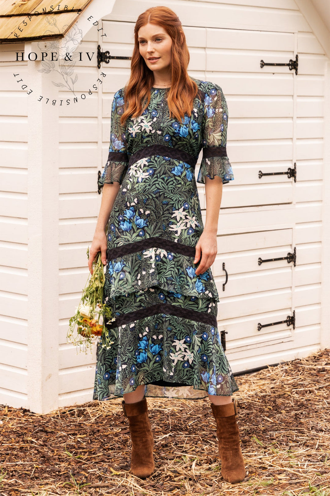 Woman in a floral dress standing in front of a white wooden door with 'Hope & Ivy' branding.