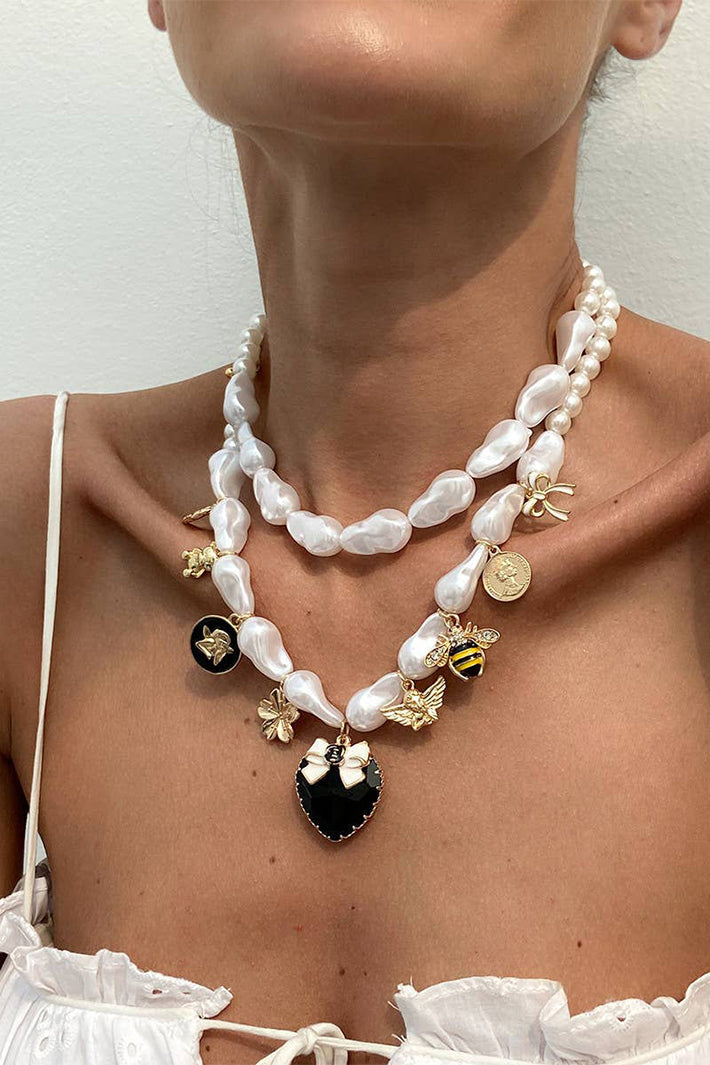 Close-up of a person wearing a pearl necklace with decorative elements on a plain background
