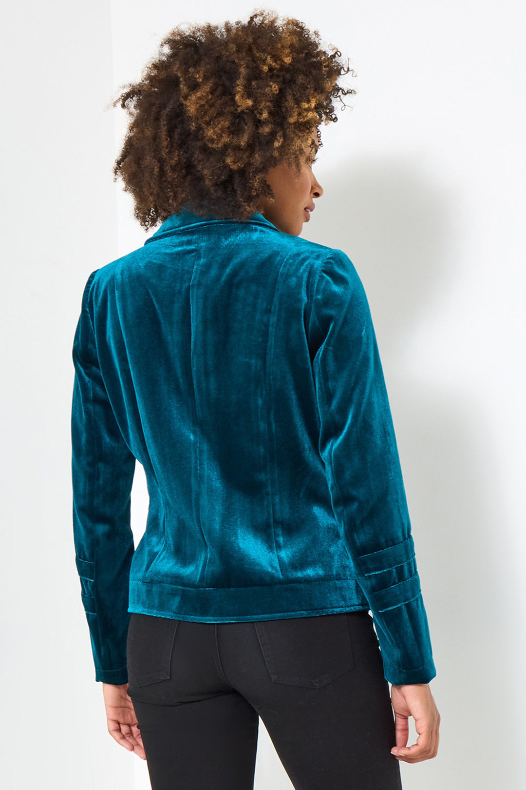 Person wearing a teal velvet jacket on a white background