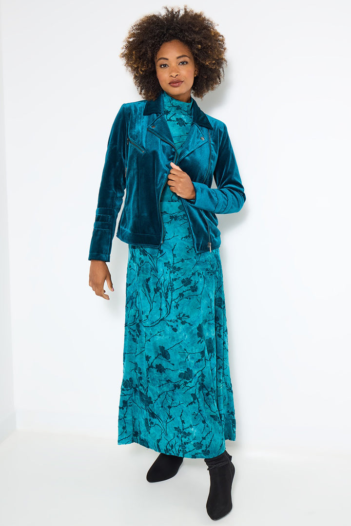 Woman wearing a teal velvet jacket and matching dress on a white background