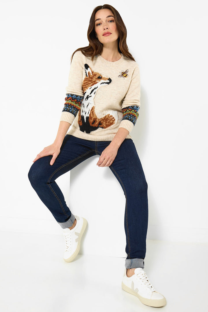 Woman wearing a sweater with a fox design and dark jeans on a white background