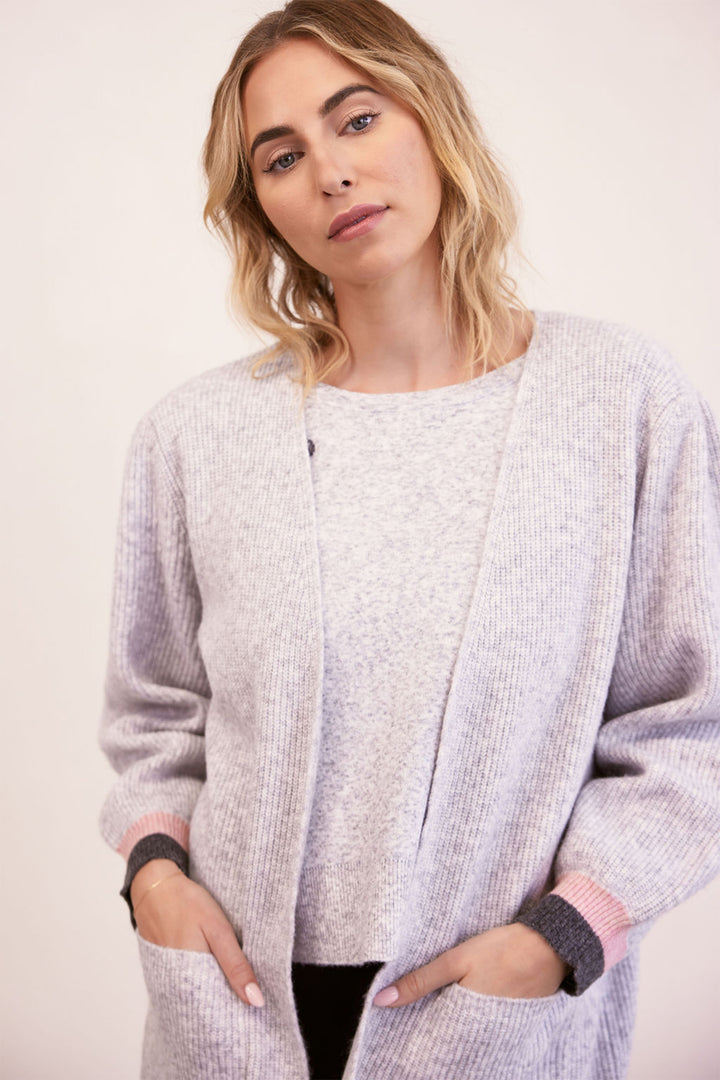 Woman wearing a light gray cardigan with a plain background