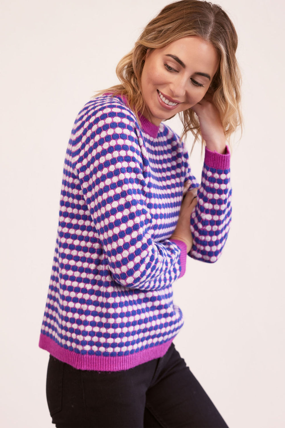 Woman wearing a purple and white patterned sweater on a plain background