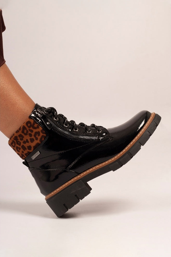 Black boots with leopard print cuff on a beige background