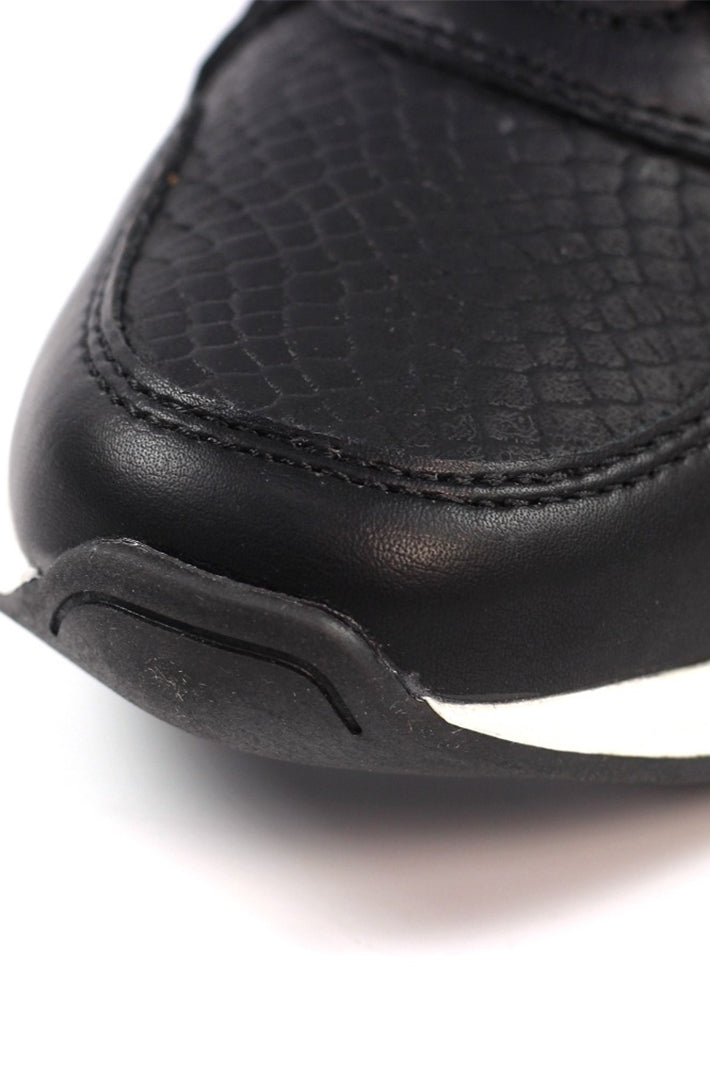 Close-up of a black leather boot with a textured pattern on a white background