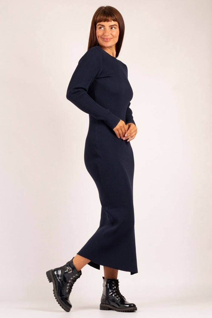 Woman wearing a navy blue dress with navy boots on a white background