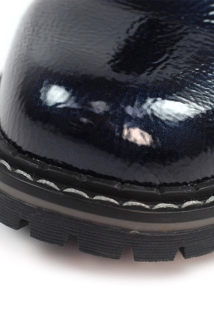 Close-up of a navy patent leather boot sole on a white background