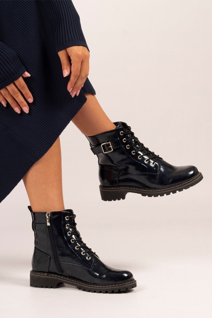 Navy leather boots worn with a navy skirt on a light background