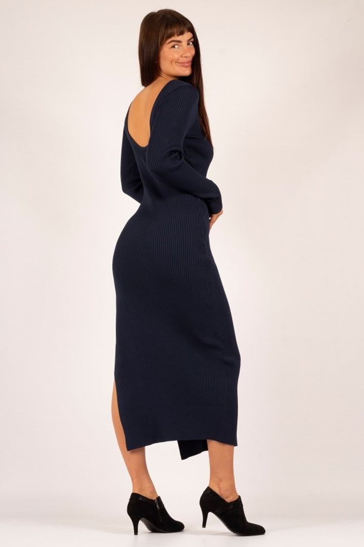 Woman wearing a navy blue dress with cut-out back on a white background