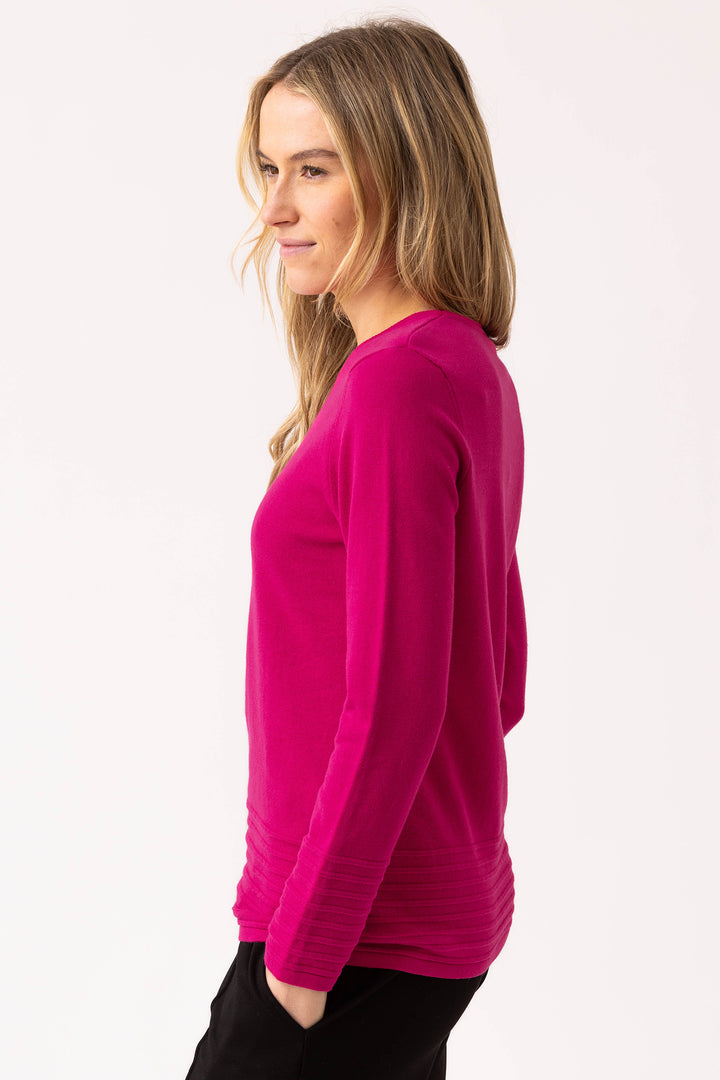 Woman wearing a bright pink long-sleeve top on a white background