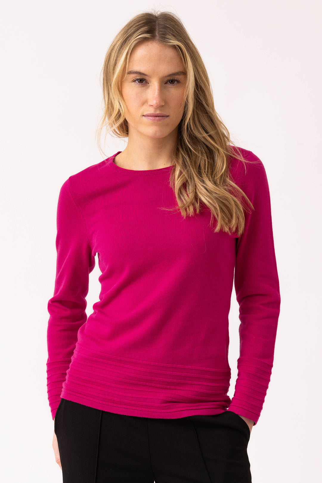 Woman wearing a bright pink long-sleeve top against a white background