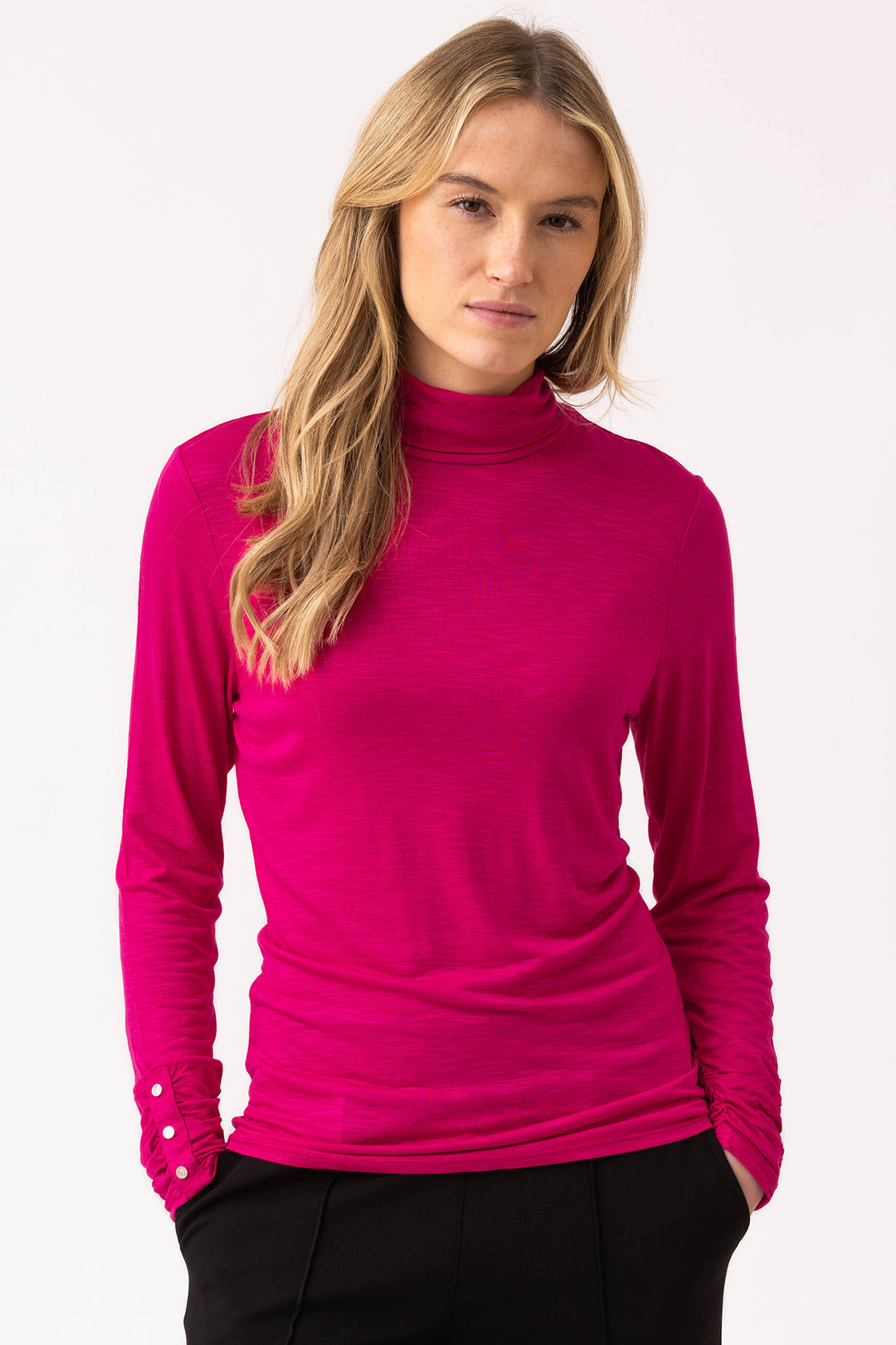 Woman wearing a bright pink long-sleeve top against a white background