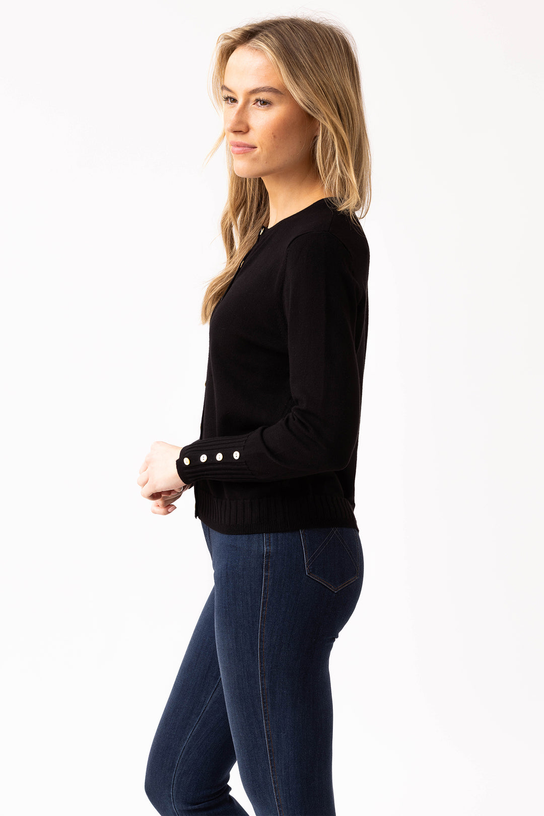 Woman wearing a black sweater with pearl buttons on a white background