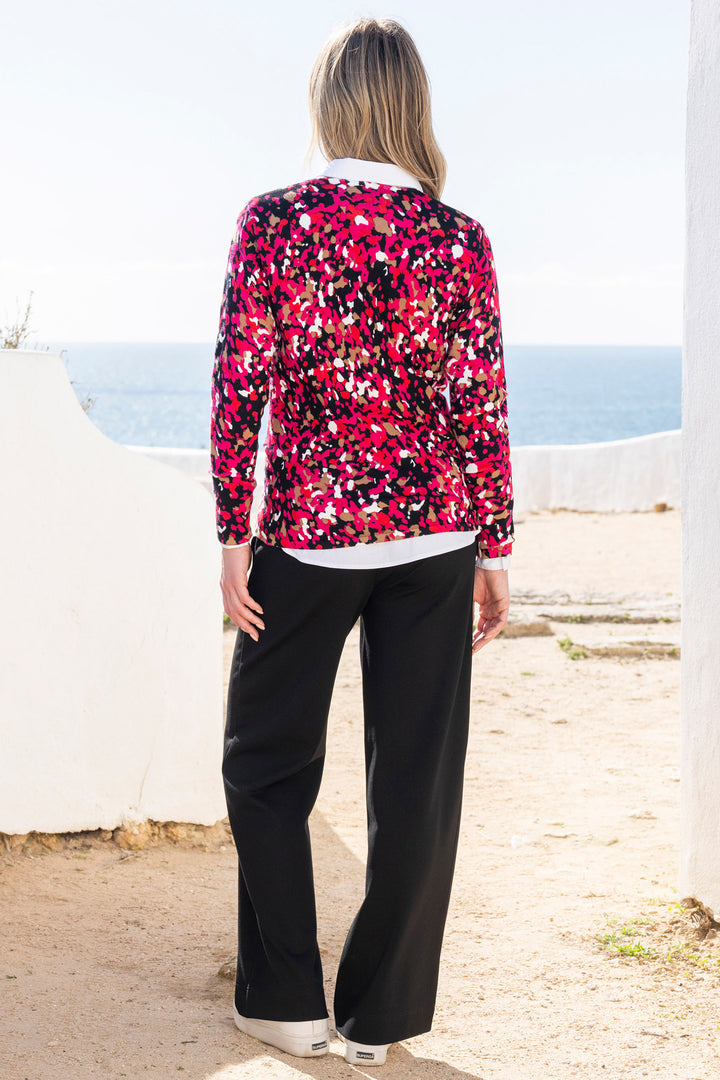Person wearing a colorful jumper and black pants standing on a coastal path.