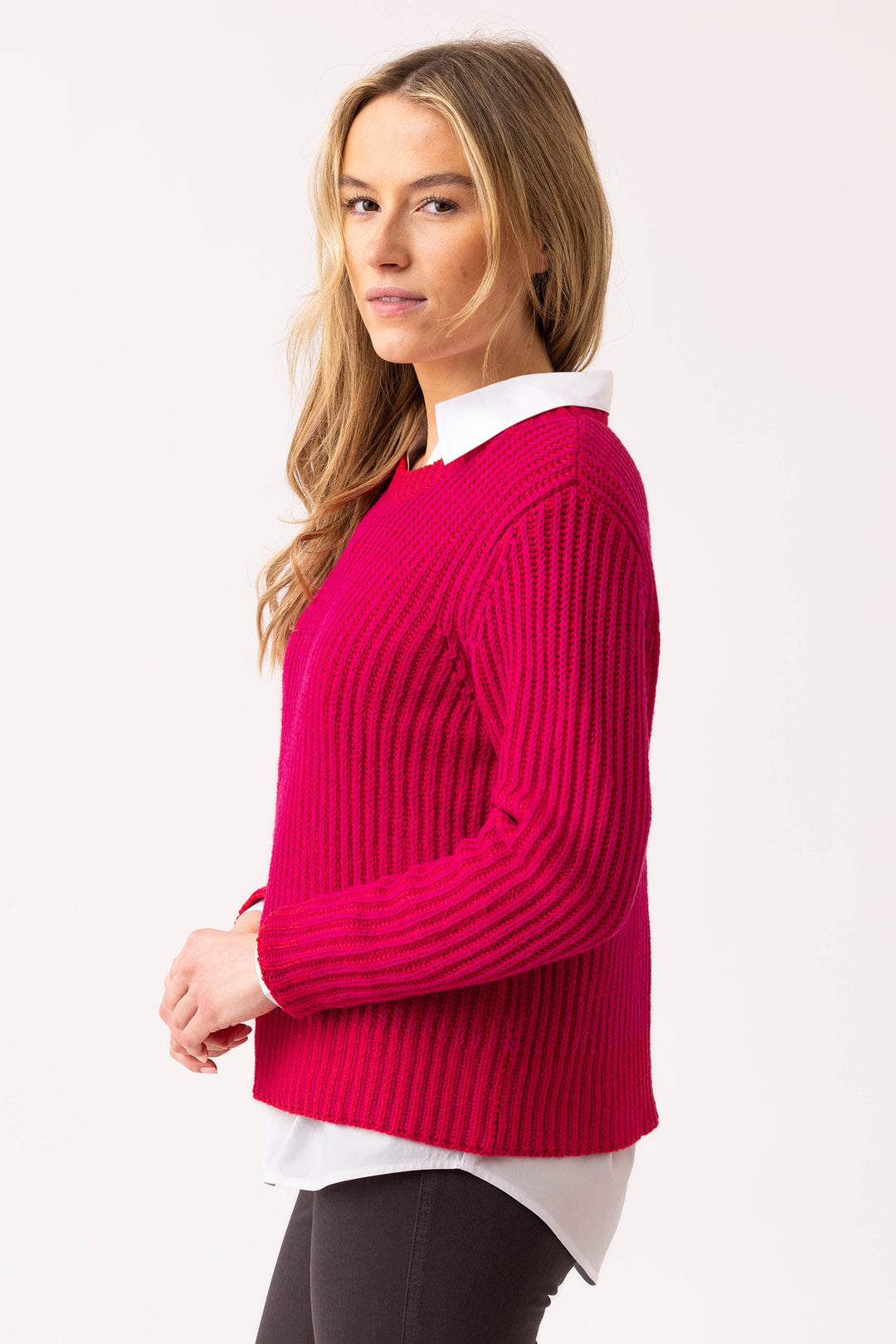 Woman wearing a bright pink sweater over a white shirt on a light pink background