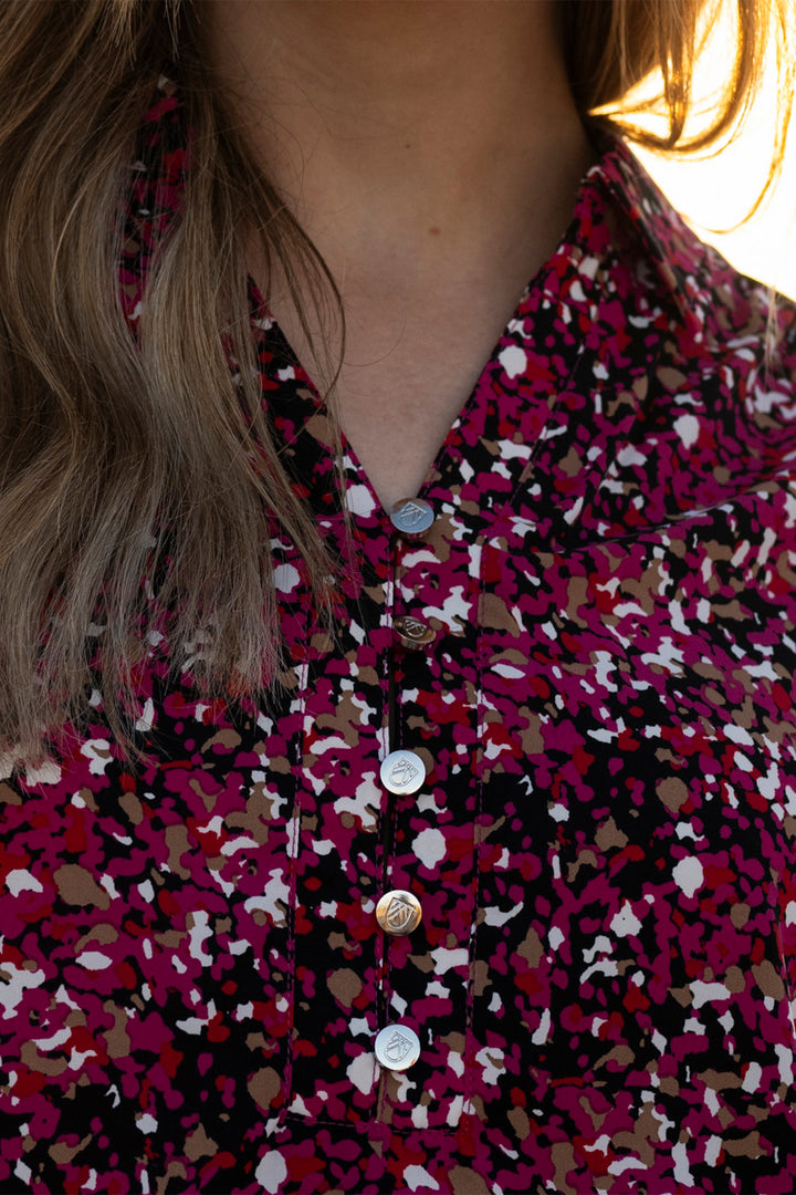 Close-up of a person wearing a floral patterned shirt with buttons.