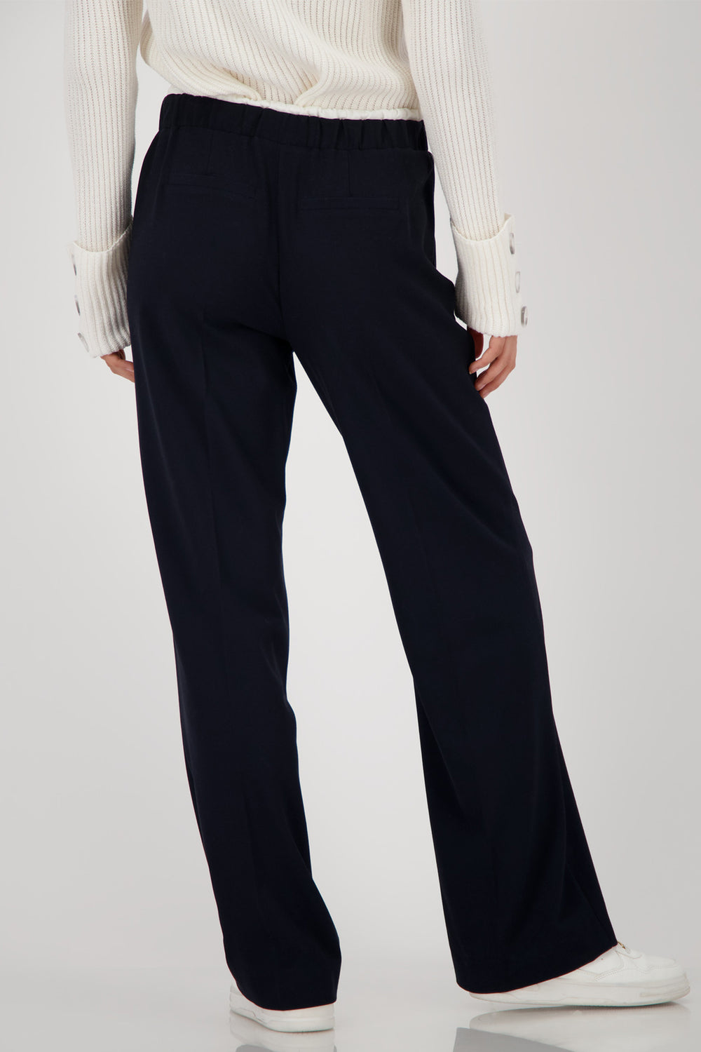 Person wearing navy wide-leg pants and a white top on a light gray background