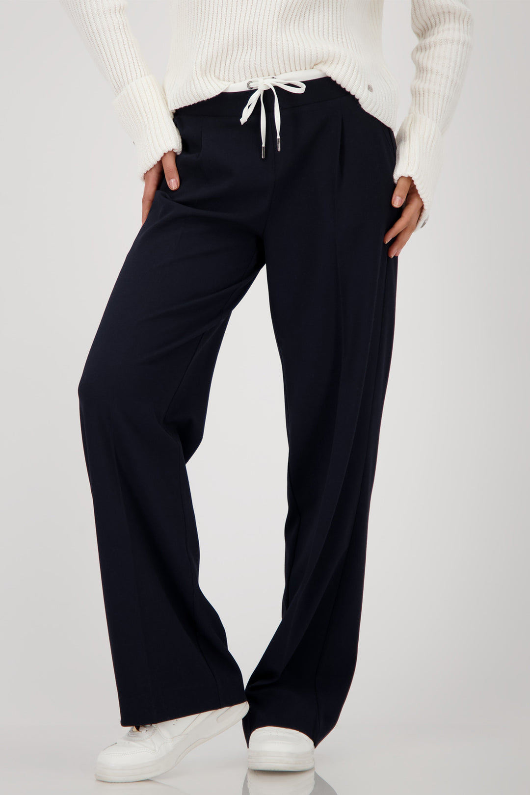Person wearing navy wide-leg pants with a white sweater on a light gray background