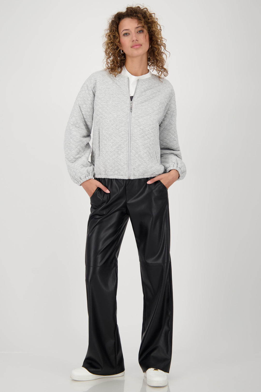 Woman wearing a gray jacket and black pants on a white background