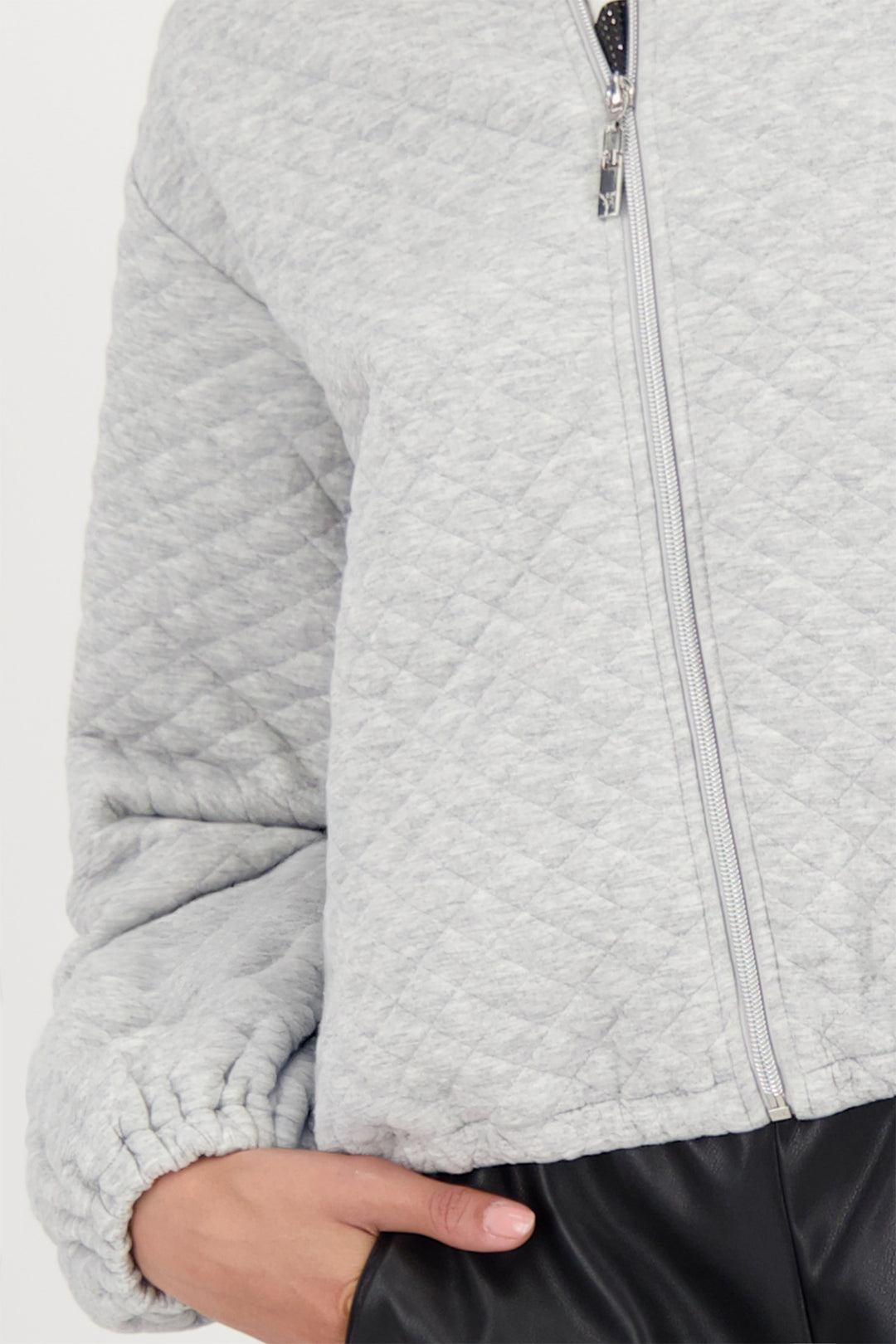 Close-up of a person wearing a gray quilted jacket with a zipper.
