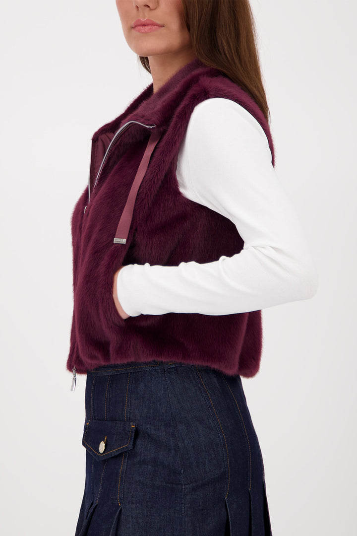 Person wearing a burgundy vest over a white shirt on a white background