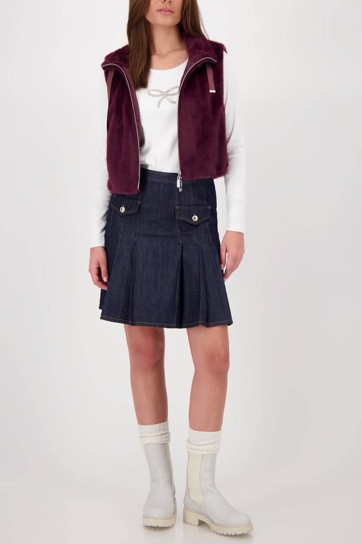 Person wearing a burgundy vest, white shirt, blue skirt, and white boots on a white background