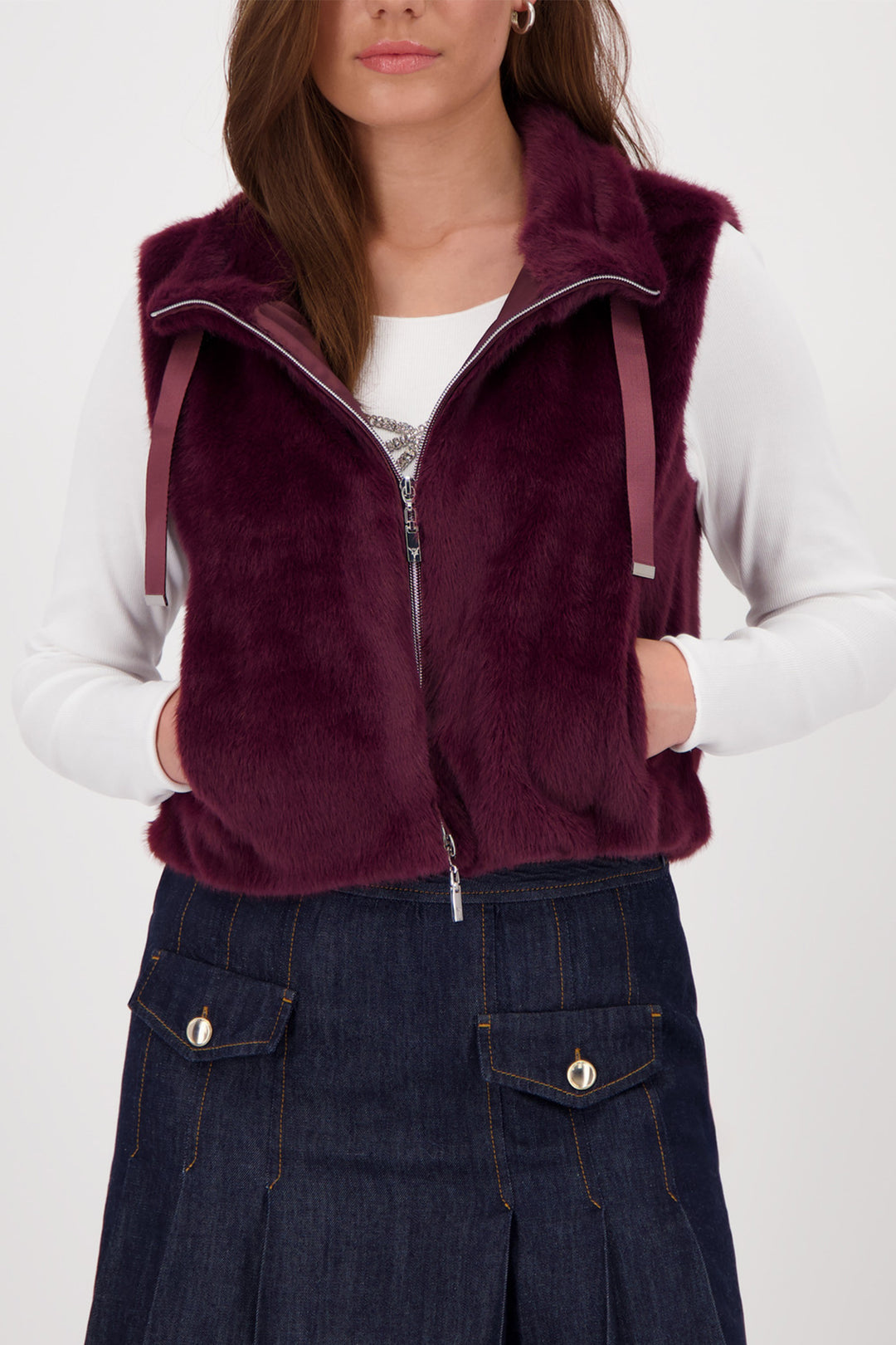 Person wearing a burgundy fleece vest over a white shirt with a plain background