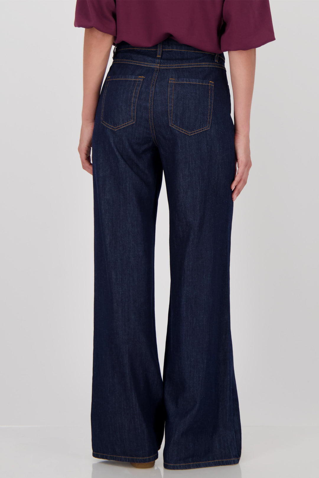 Person wearing dark blue wide-leg jeans on a white background