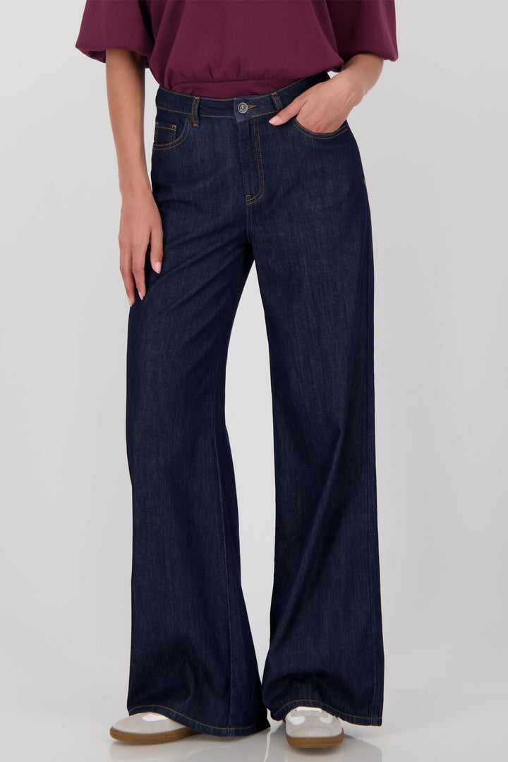 Person wearing dark blue wide-leg jeans on a white background