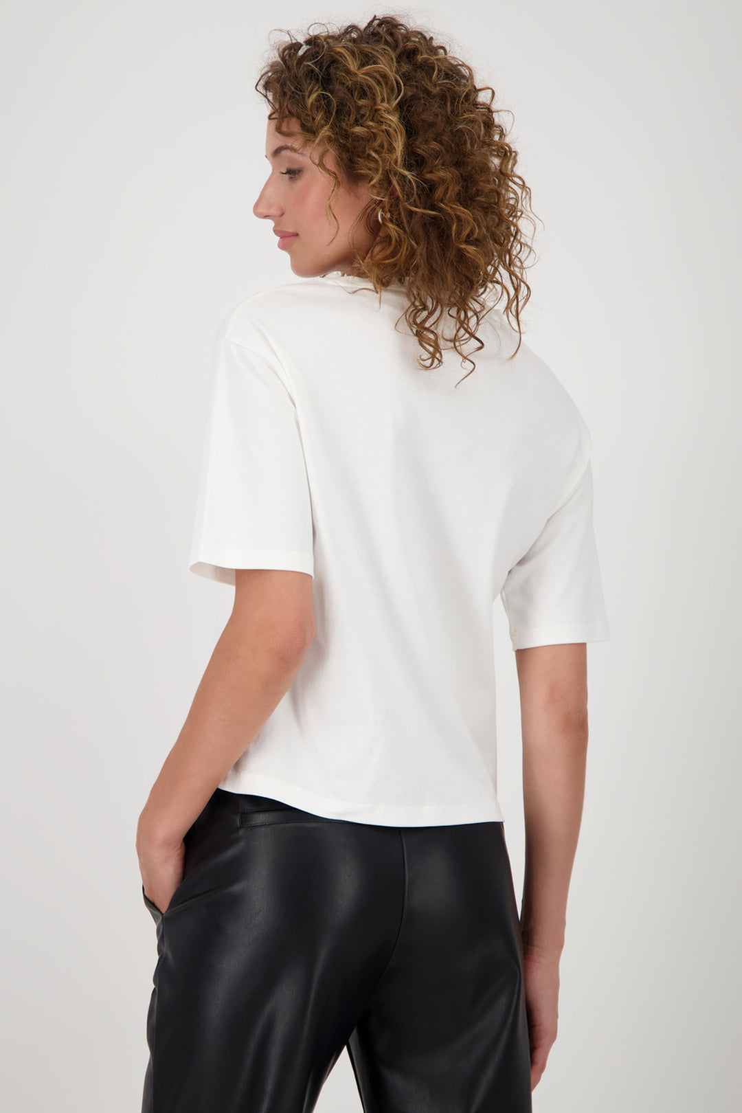 Person wearing a white t-shirt and black pants on a plain background