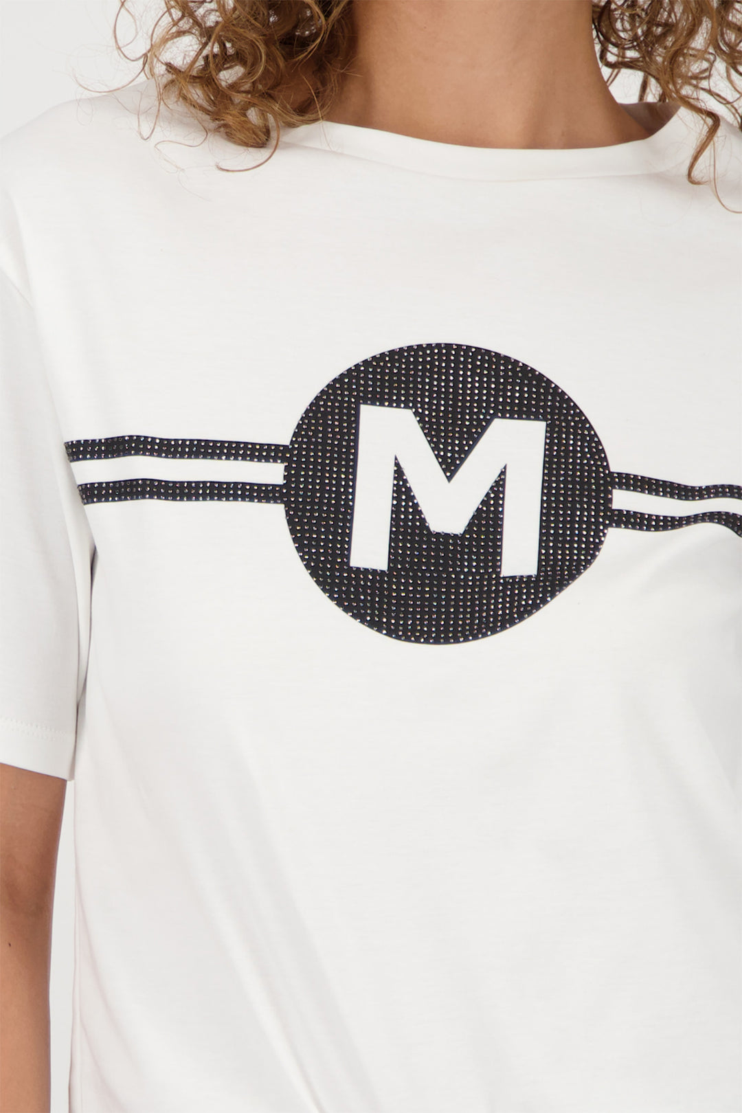 White t-shirt with a black circle and letter 'M' on a person wearing it.