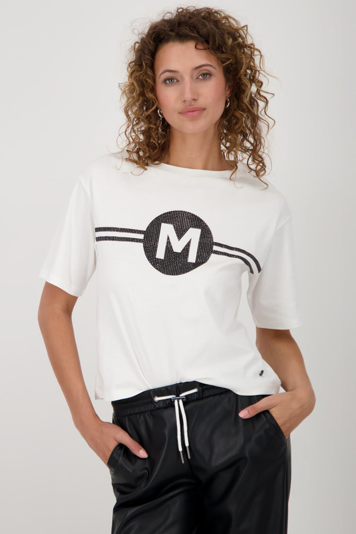 Woman wearing a white t-shirt with a black 'M' logo on a plain background