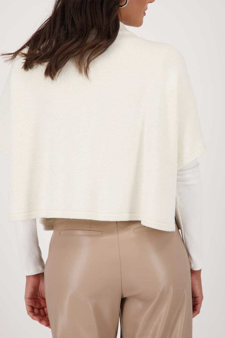 Person wearing a white top and beige pants on a plain background