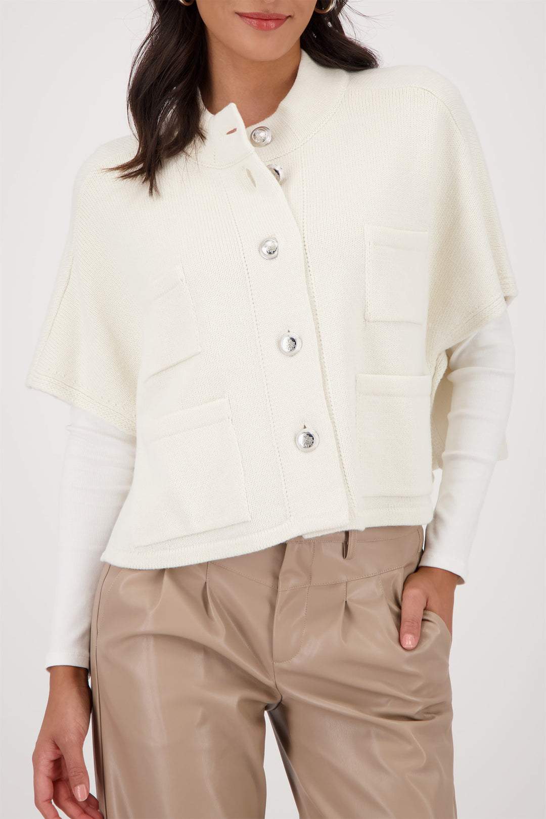 Person wearing a white button-up shirt and beige pants on a white background