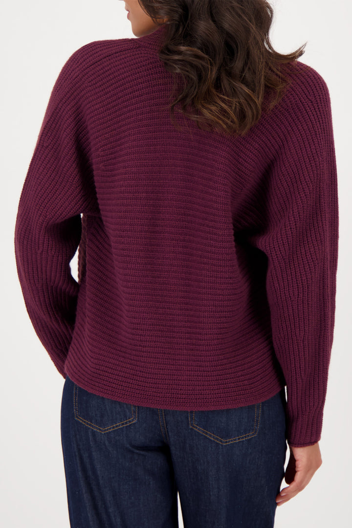 Person wearing a maroon sweater and blue jeans on a white background